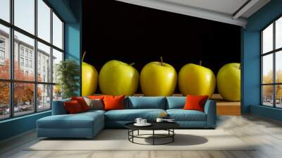 all different, all equal - five apples in a row over wooden table against a black background Wall mural