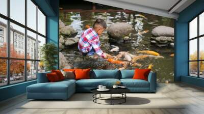 Happy kids walk with fun by pond stepping stones, feeding golden koi fishes in Tirta Gangga garden with natural water pools. Culture, arts of Bali, popular travel destination in Indonesia. Wall mural