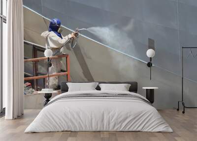 worker painting ship hull using airbrush gray paint Wall mural