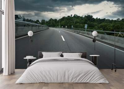 Highway overpass motion blur with forest background and dark storm clouds Wall mural