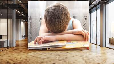 The child was tired of studying, he lowered his head to the books. Wall mural