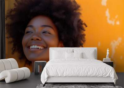 A joyful woman with a stylish afro laughs in front of a blue wall Wall mural