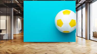 Top view photo of white and yellow soccer ball as football concept . Minimalist flat lay image of leather football ball over blue turquoise background with copy space and right side composition. Wall mural