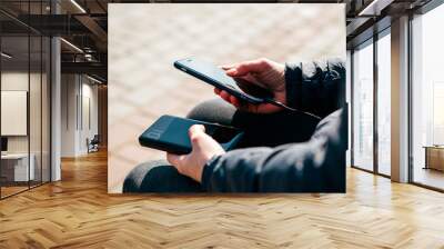 man hands holding black smartphone charging battery from external power bank Wall mural