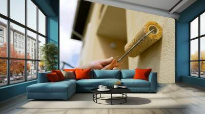 Medium shot of a wall painting, an industrial worker uses a roller and other tools to paint the walls of a new home. A maintenance worker uses a roller brush to paint a residential building. Wall mural