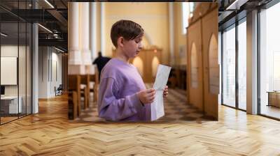 a boy stands in front of a confessional in a Catholic church, preparing for his first confession Wall mural