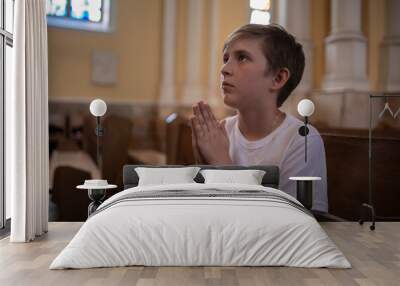 little boy prays in the temple. child, catholic communicates with God in church, cathedral. Wall mural