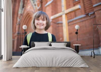 smiling happy child  goes to Sunday school in the temple, stands in front of the Catholic Cathedral Wall mural