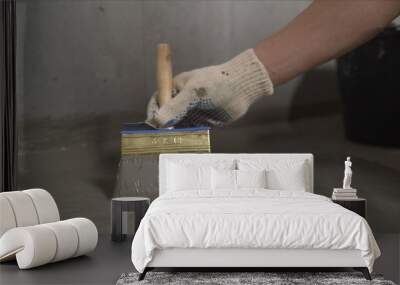 Waterproofing concrete floor with mortar and brush. An industrial worker at a construction site installs a sealant for waterproofing cement.  Wall mural