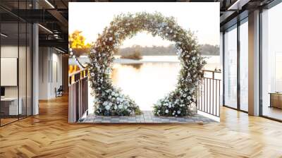 Circle wedding arch decorated with white flowers and greenery outdoors. Wall mural