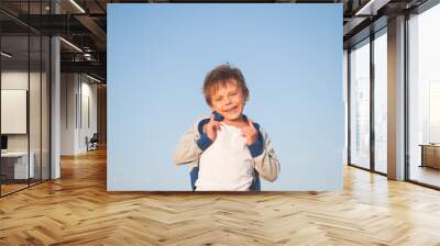 happy delightful laughing little child in sweater on blue sky background Wall mural