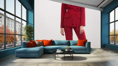 young elegant woman in red trouser suit standing in the studio on gray background Wall mural