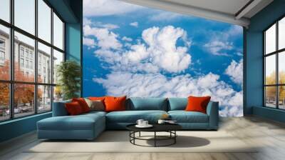 Serene view of the sky from an airplane with scattered white clouds above. The clouds are white and fluffy, giving the sky a dreamy and peaceful atmosphere Wall mural