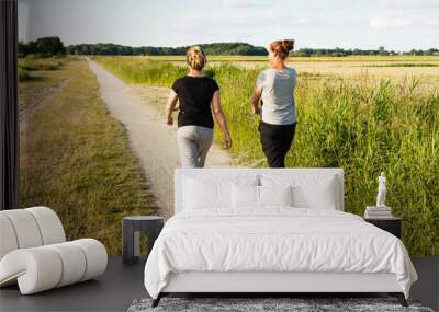 two women walking on sandy path Wall mural