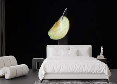 A slice of apple on a knife on a black background. Sliced green apple slice Wall mural