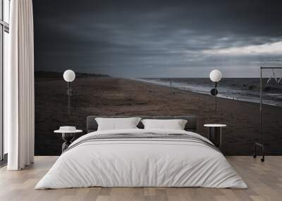 A man wades alone into the ocean on the beach at sunrise on a stormy day. Wall mural