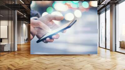 Closeup image of male hands with smartphone at night on city street, searching internet or social networks, hipster man typing an sms message on chat Wall mural