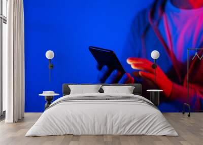 Male hand with smartphone. Finger typing on screen. Neon light Wall mural