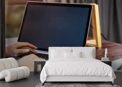 Mockup image of a woman using laptop with blank screen on wooden table Wall mural