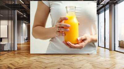 Woman holding a glass bottle of orange juice Wall mural