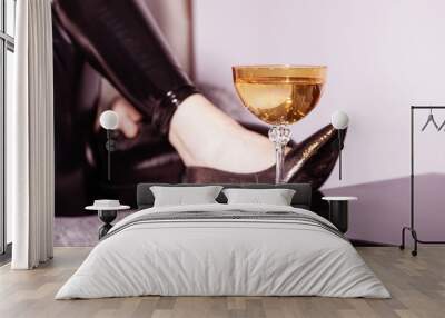 Woman legs with black trousers and fancy high heel shoes placed leg on black mirror table with fancy drink glass on it with copy space. Glass is in camera focus. Pink color gradient map applied Wall mural