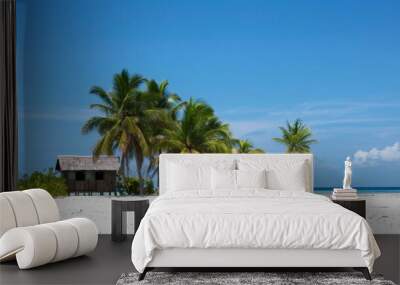 Caucasian Woman and Man in Their 30s Relaxing at a Wooden Beach Hut on a Tropical White Sandy Beach Surrounded by Palm Trees Under a Clear, Bright Sky During Midday, Exuding a Tranquil and Relaxing Mo Wall mural