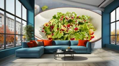 Green salad with pineapple chunks and pomegranate seeds, fresh and colorful in a speckled bowl Wall mural