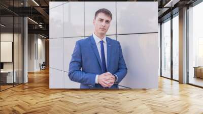 Portrait of a young businessman standing over blurred background outdoors Wall mural