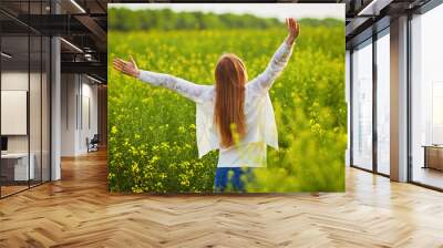 woman with open arms in the green rapeseed field. Wall mural