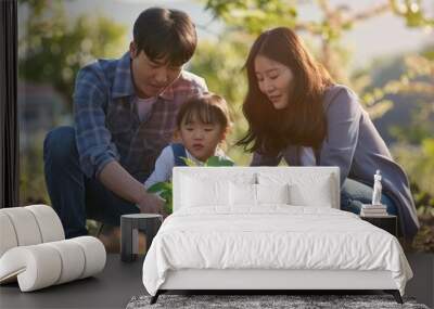 Young Asian Family Planting Sapling in Garden at Sunset—Togetherness and Eco-Friendly Lifestyle Wall mural