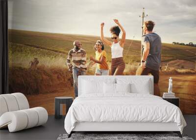 Friends, nature and dance with a man and woman group outdoor in a desert on a sand road with freedom. Travel, summer or vacation with young people enjoying a holiday together and laughing or joking Wall mural