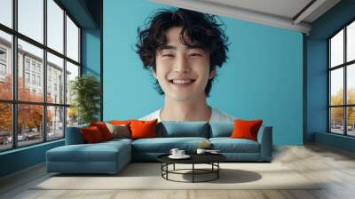 Asian man in white t-shirt smiling with confidence on blue background. Wall mural