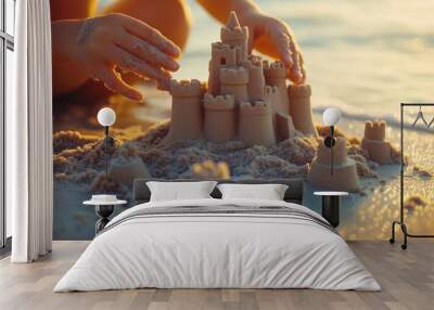 Close-up of hands and castle structure, child building a sand castle on the beach. Wall mural