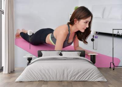 Concept of exercise. Beautiful girl is exercising in her house. Beautiful girl takes good care of her health. Wall mural