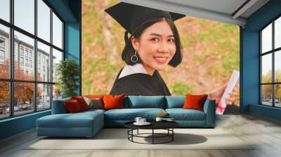 Graduation Concept. Graduated students on graduation day. Asian students are smiling happily on the graduation day. Students wear graduation gowns in the garden Wall mural