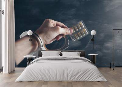 hand in handcuffs and pills on a gray background Wall mural