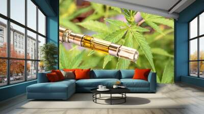 oil filled vape pen cartridge up-close against green cannabis leaf background Wall mural