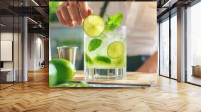 A bartender garnishing a cocktail with a slice of lime and mint leaves, creating a refreshing drink. Wall mural