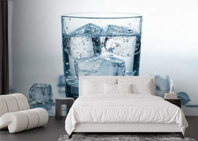 A glass of clear water with ice cubes, condensation on the outside, set against a bright white background. Wall mural