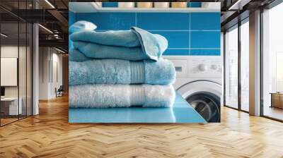 A stack of blue towels sits on a blue counter in front of a white washing machine. Wall mural