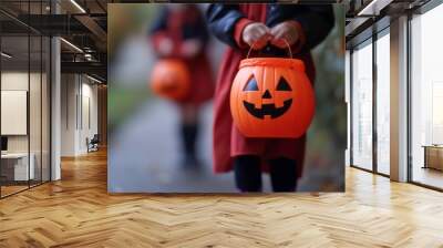 Close up of a child holding a pumpkin-shaped Halloween trick or treat bucket. Wall mural