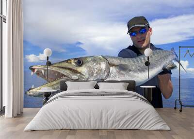 Deep sea fishing, catch of fish, big game fishing, fisherman holding a giant barracuda Wall mural