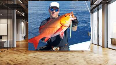 fisherman holding a big red snapper fish, deep sea fishing, lure fishing, big game fishing. Catch of fish Wall mural