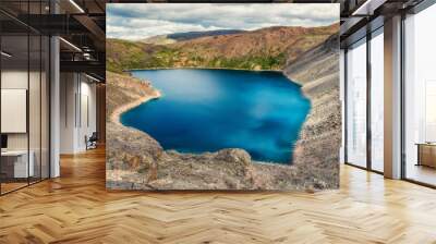 Blue mountain lake in the caldera. Mountain range against a cloudy sky. Caldera of an extinct volcano is surrounded by a mountain range. In the valley there is a blue lake with steep rocky shores. Wall mural