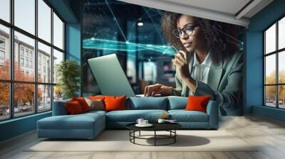 Woman with afro hair sltyle sitting and working with laptop in her office. Wall mural