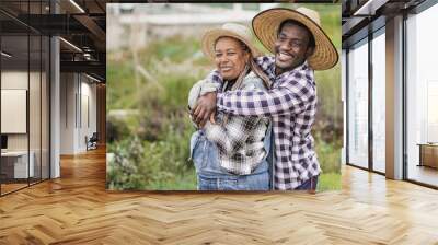 African farmer people having fun together during harvest period - Farm lifestyle - Black mother and adult son hugging each other Wall mural