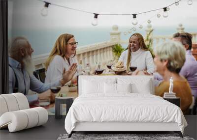 Cheerful multiracial senior friends having fun at a dinner outdoor on patio Wall mural