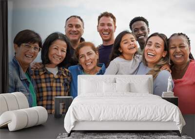 Group of multigenerational people hugging each other while smiling on camera - Multiracial friends having fun together outdoor Wall mural