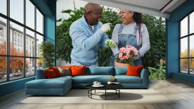 Happy african senior couple having fun gardening together at house patio Wall mural