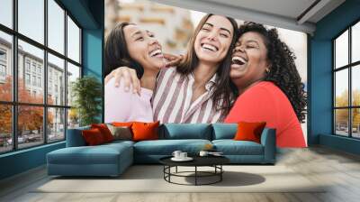 Happy latin women laughing and hugging each other outdoor in the city - Millennial girls and friendship concept Wall mural